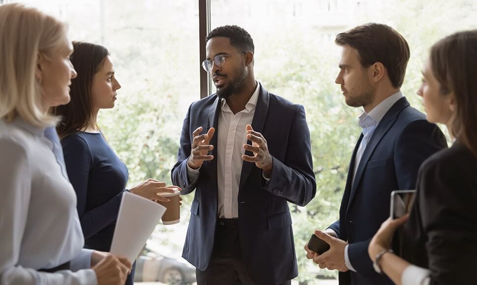 A mixed group of office workers engages in discussion.