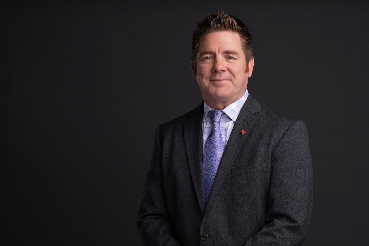 Hal Morgan wearing a grey suit, violet button-down shirt and a violet tie.