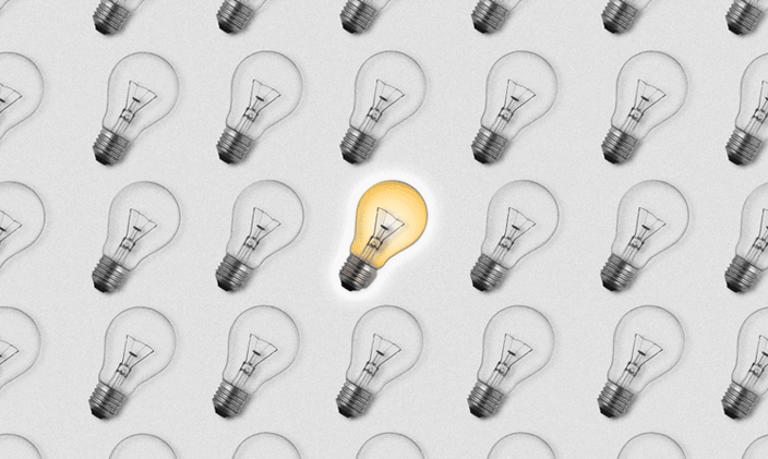 Black and white lightbulbs fill the frame with a single yellow bulb illuminated in the center.