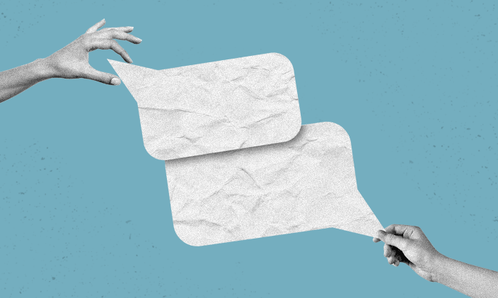 Two hands extended toward one another each holding a white paper text bubble.