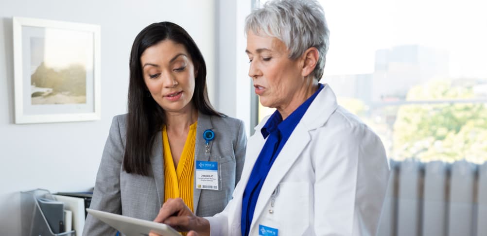 Two healthcare workers collaborating in an office with a tablet