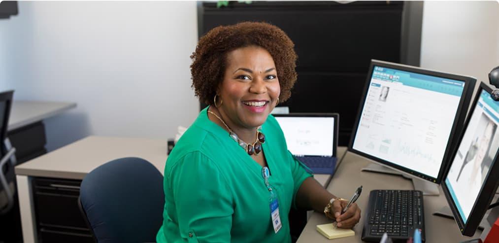 Woman smiling and working on a computer in a work setting