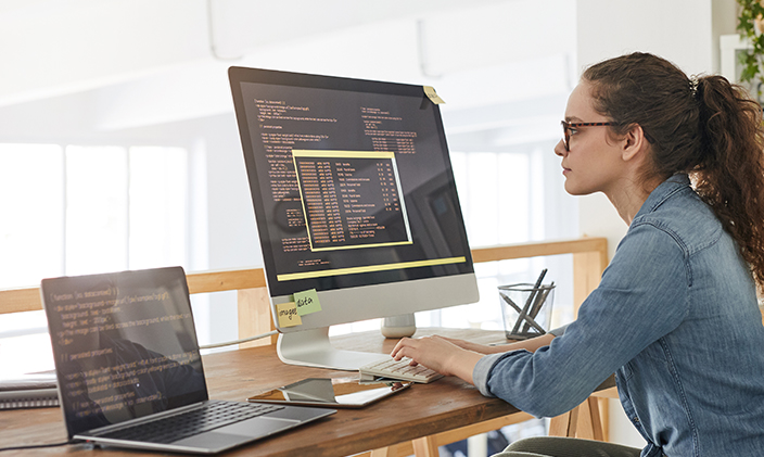 A researcher dives deep into a topic using a large monitor and laptop