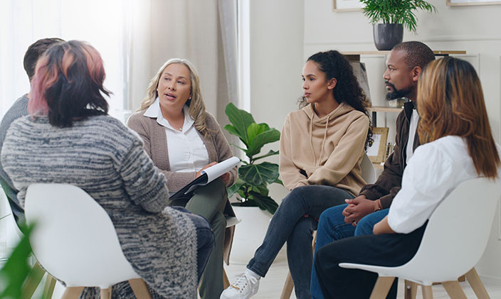 A group of doctoral students sit in a circle and participate in a discussion